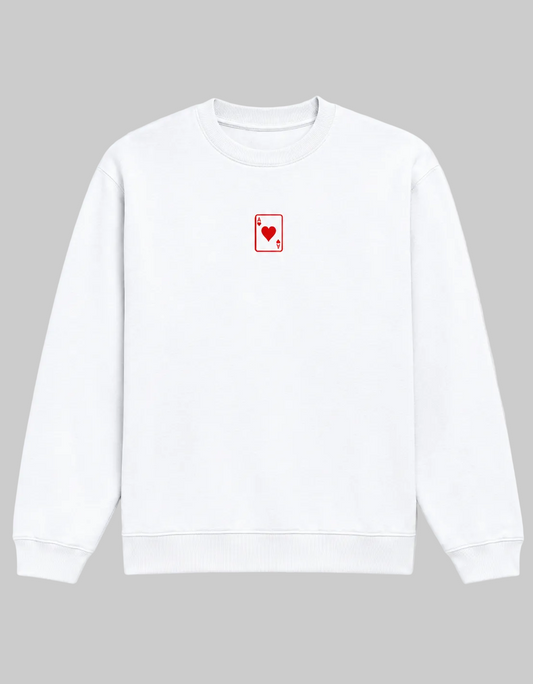 A white crewneck sweatshirt featuring a small red playing card (Ace of Hearts) graphic on the left chest, displayed against a clean white background.